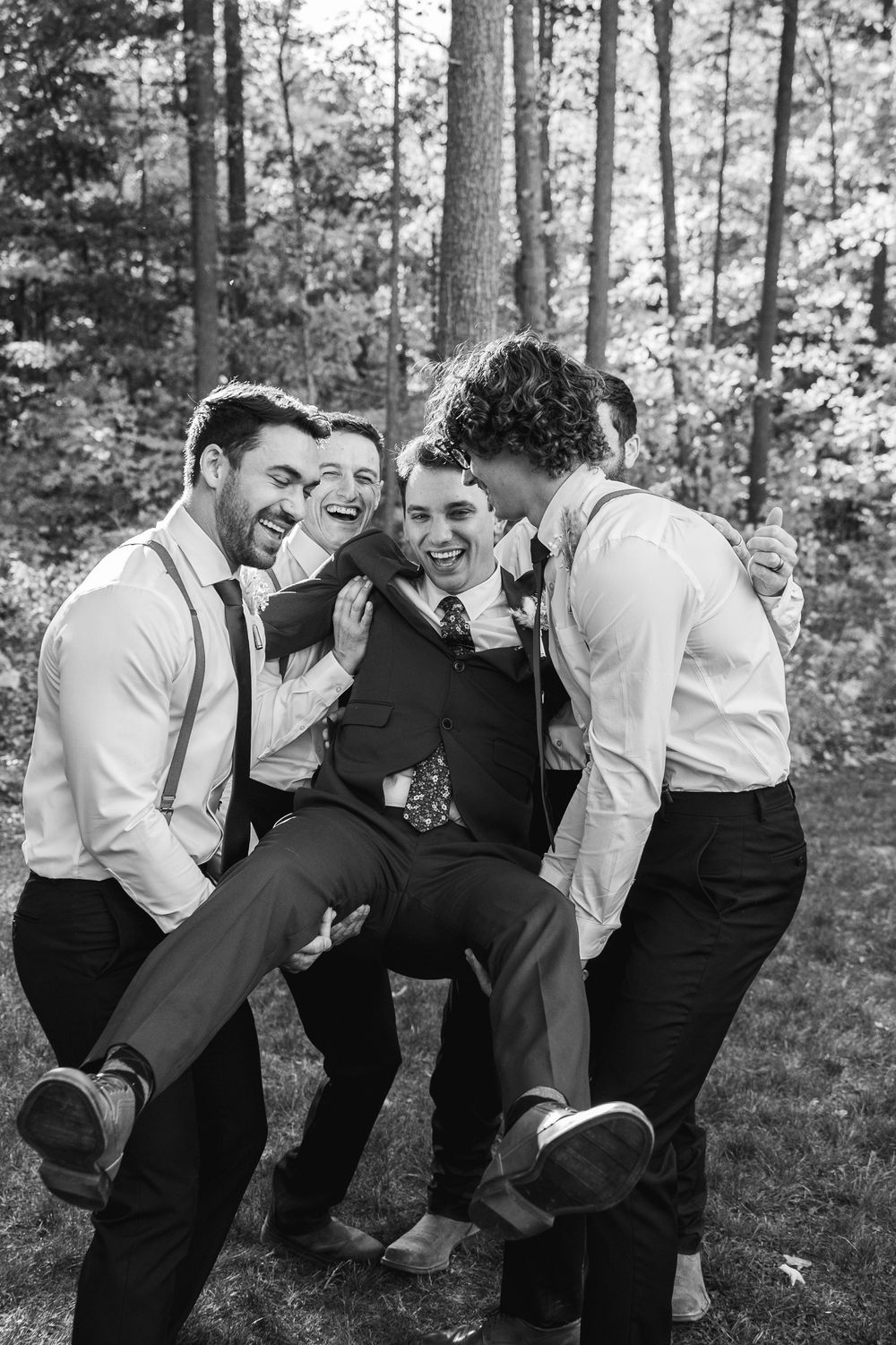 Black and white photo sequence showing groomsmen laughing and falling over in a playful domino effect outdoors.