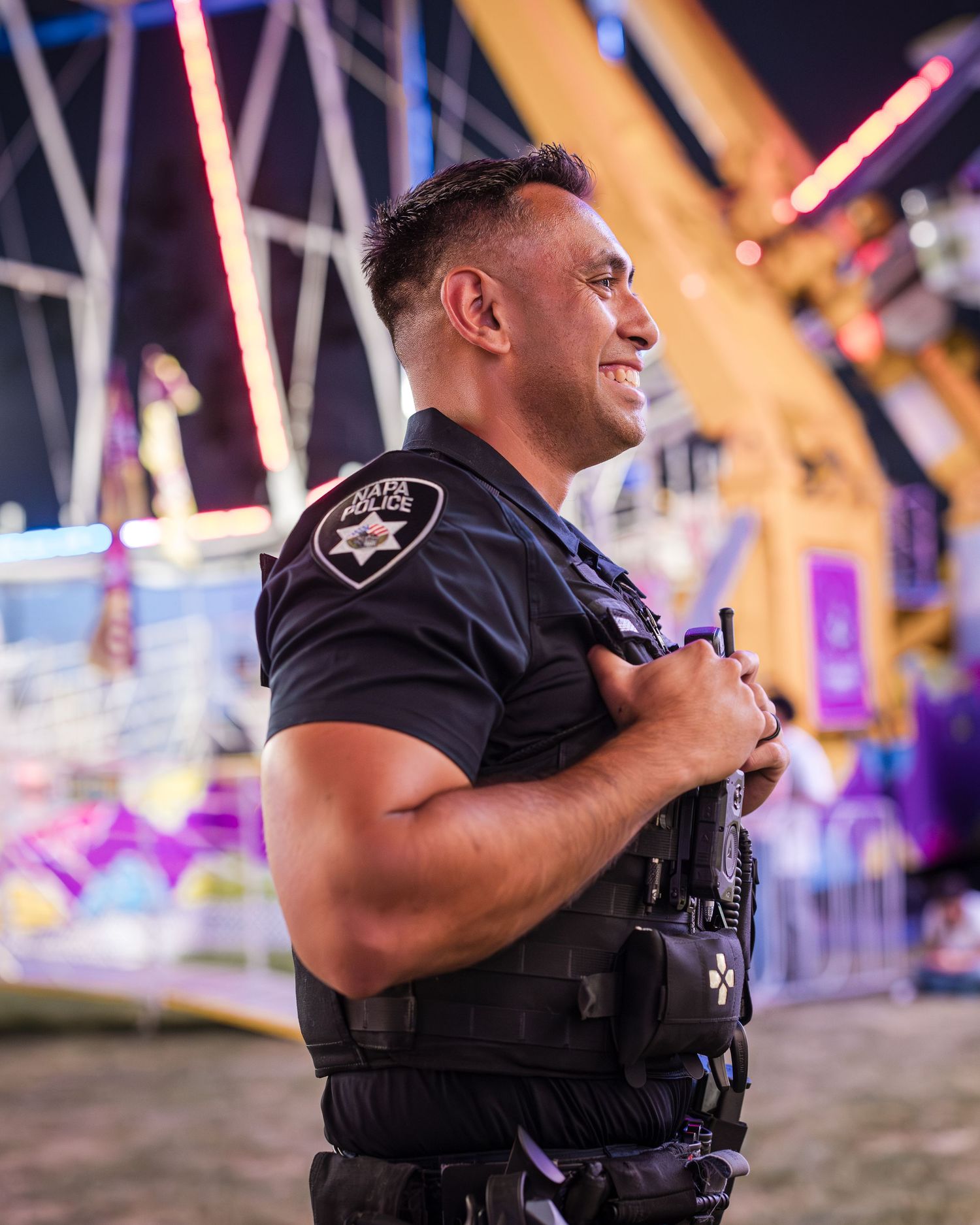 Police officers patrolling at night with colorful carnival lights in background.