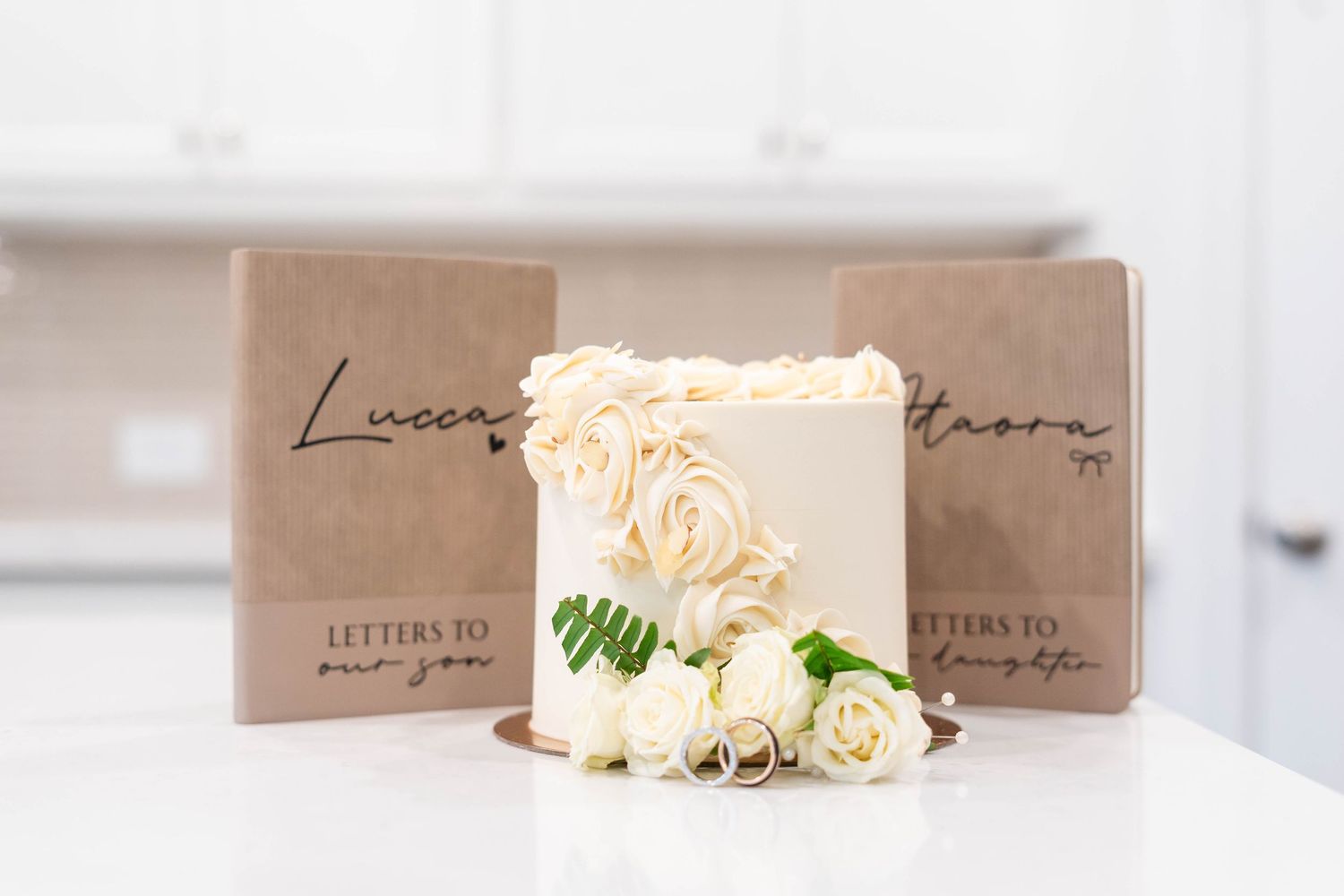 Elegant white rosette wedding cake displayed with kraft paper Letters to Our Son and Daughter keepsake books.