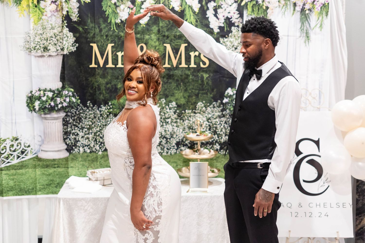 Bride and groom dancing under Mr. & Mrs. sign at elegant floral wedding reception backdrop.