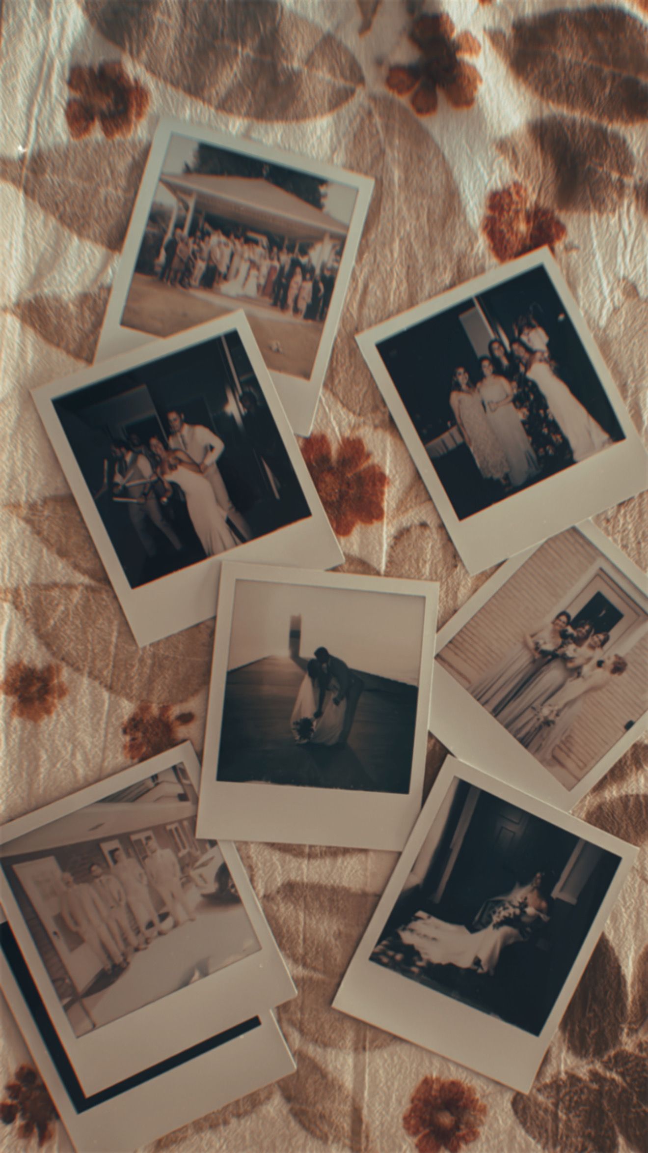A collection of vintage Polaroid photographs scattered on a floral patterned fabric surface.
