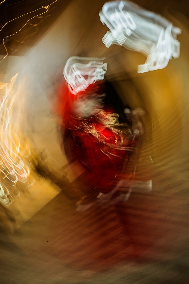 Abstract light trails create swirling patterns of red and gold in a long exposure photograph.