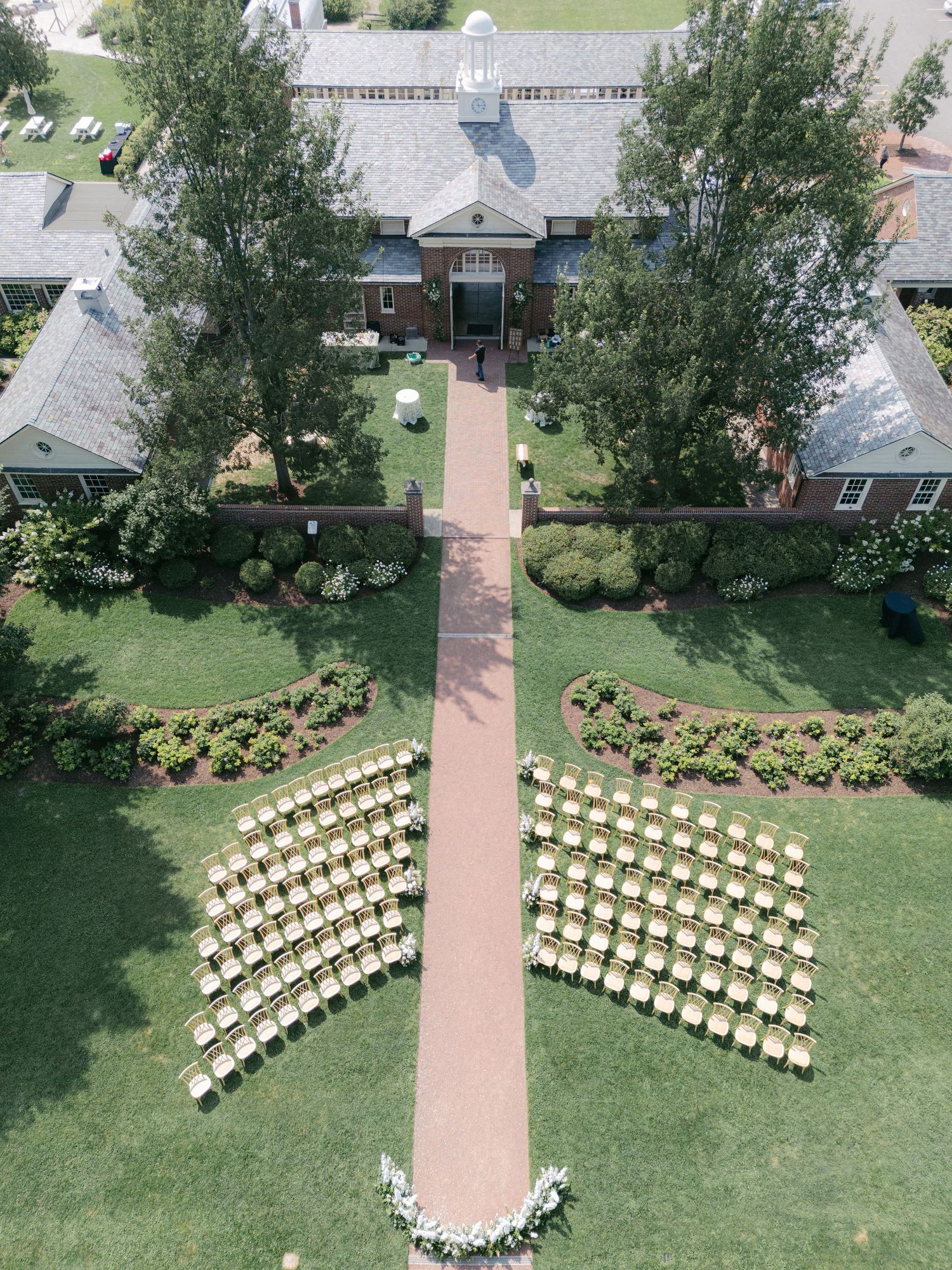 Aerial view of white chairs arranged in curved rows on a green lawn for an outdoor wedding ceremony. - Elawa Farm