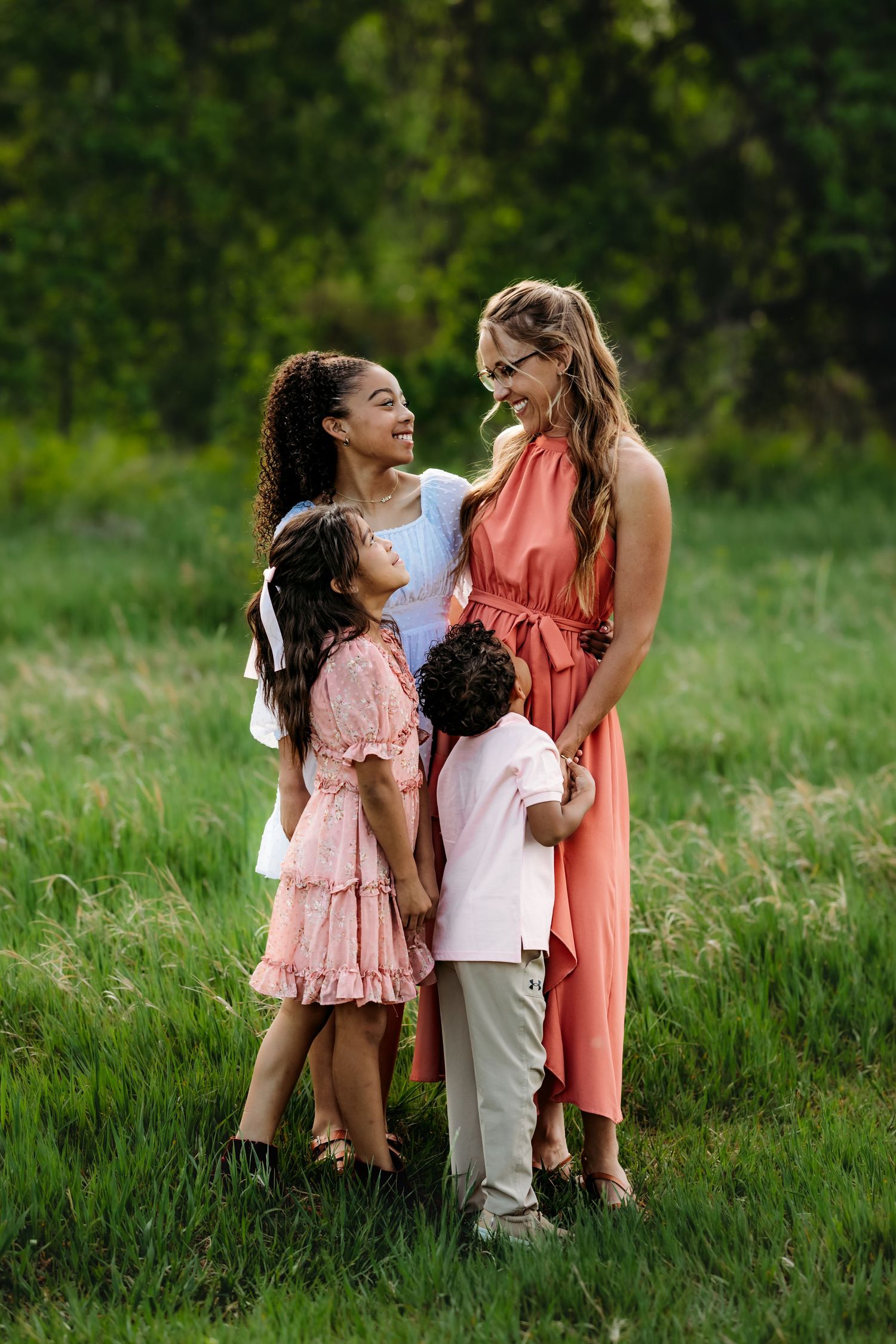 A family shares joyful moments together in a lush green field on a sunny afternoon.