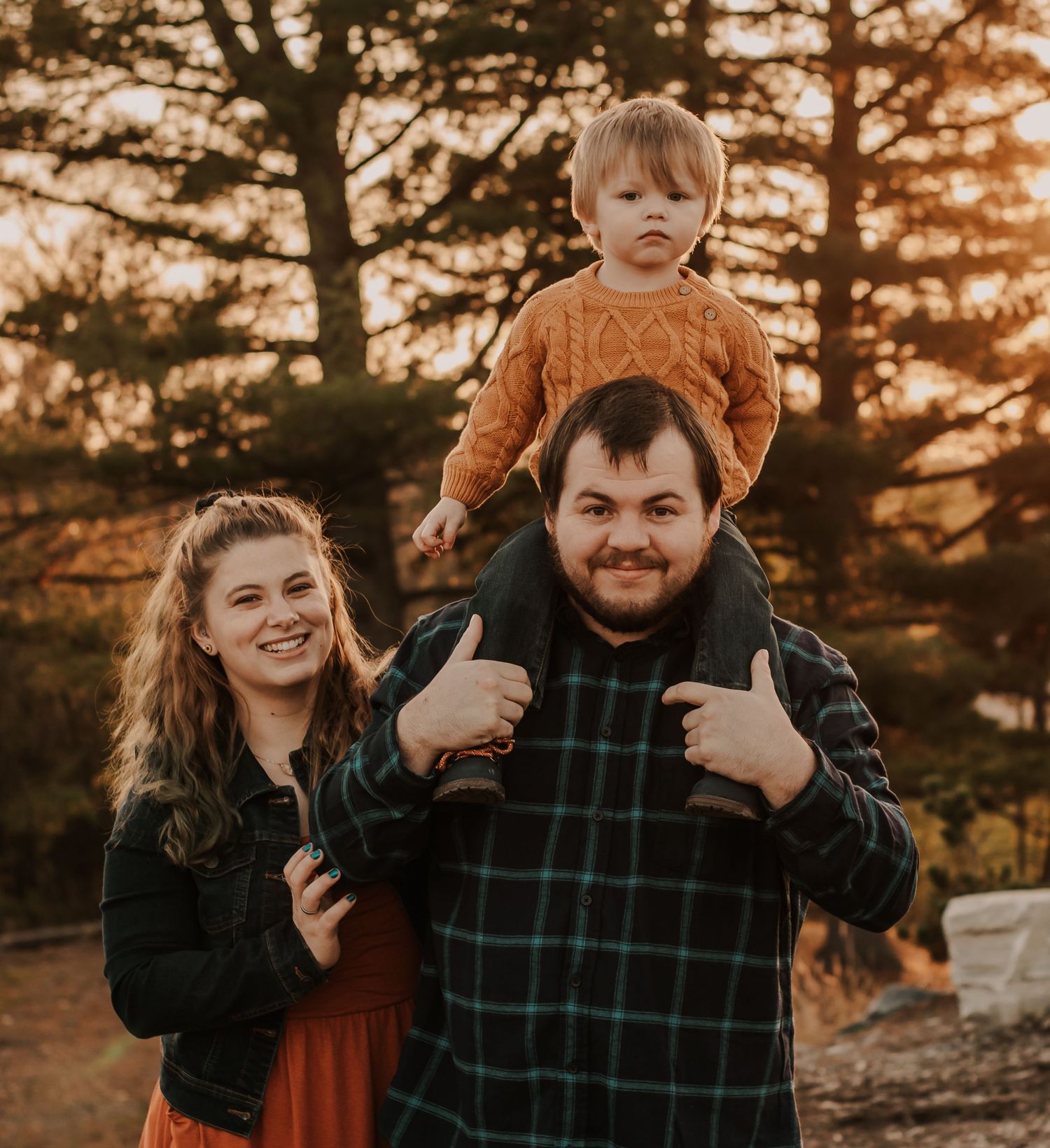 A joyful autumn family portrait with sunset lighting through the trees.