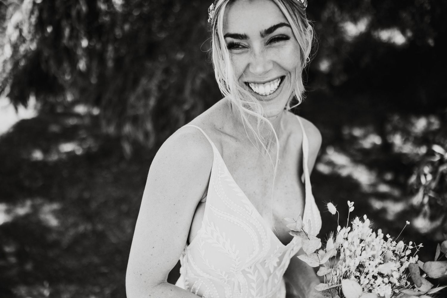 Black and white portrait of smiling bride holding elegant white bouquet.