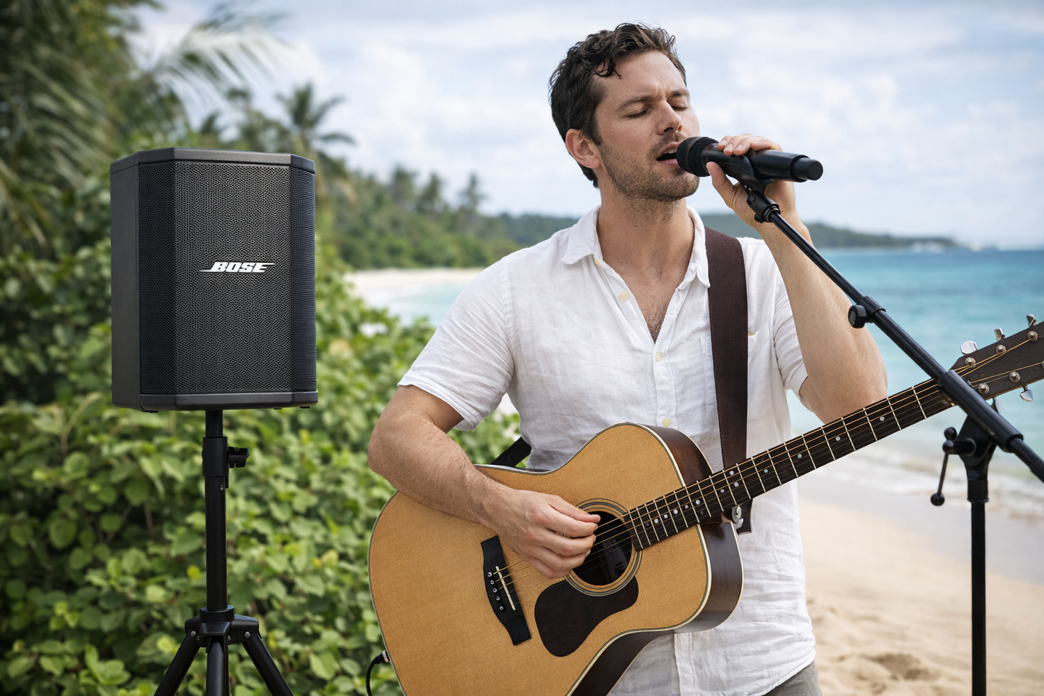 A musician performs with an acoustic guitar on a tropical beach with palm trees and ocean views in the background.
