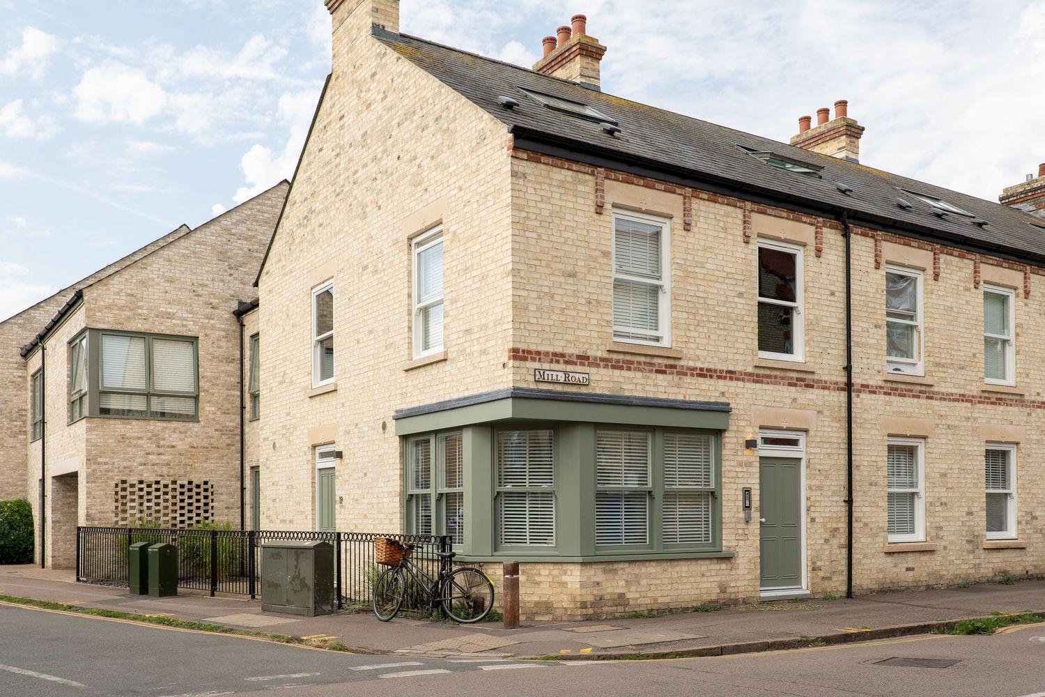 Corner property with bay windows and light colored stone exterior on a residential street in England.