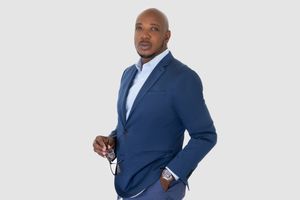 Professional headshot of a confident real estate agent holding glasses in business attire