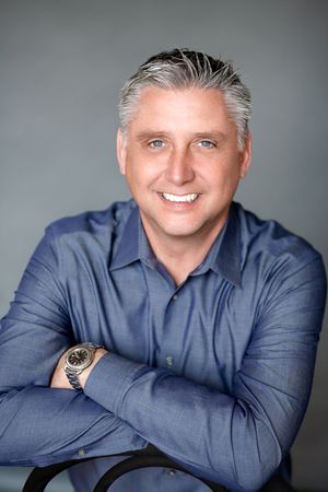 Professional headshot of a confident real estate agent smiling in business attire