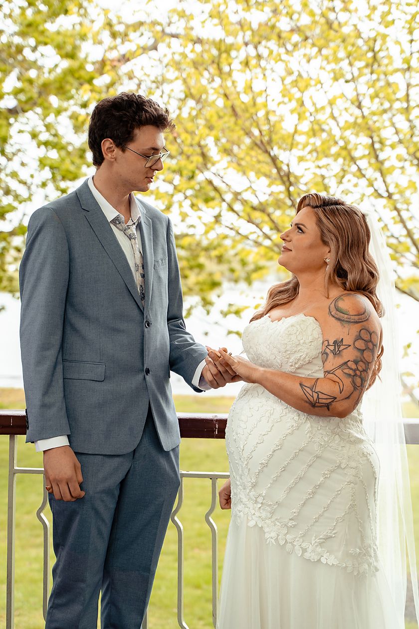 A couple shares an intimate moment on their wedding day with autumn foliage in the background.