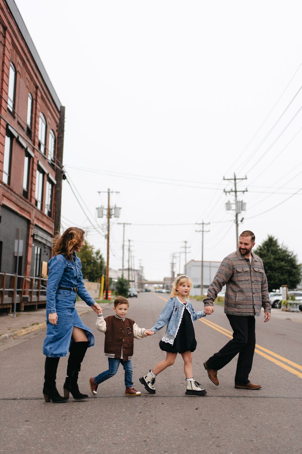 A series of five connected photos showing playful poses on a street with brick buildings and utility poles in the background.