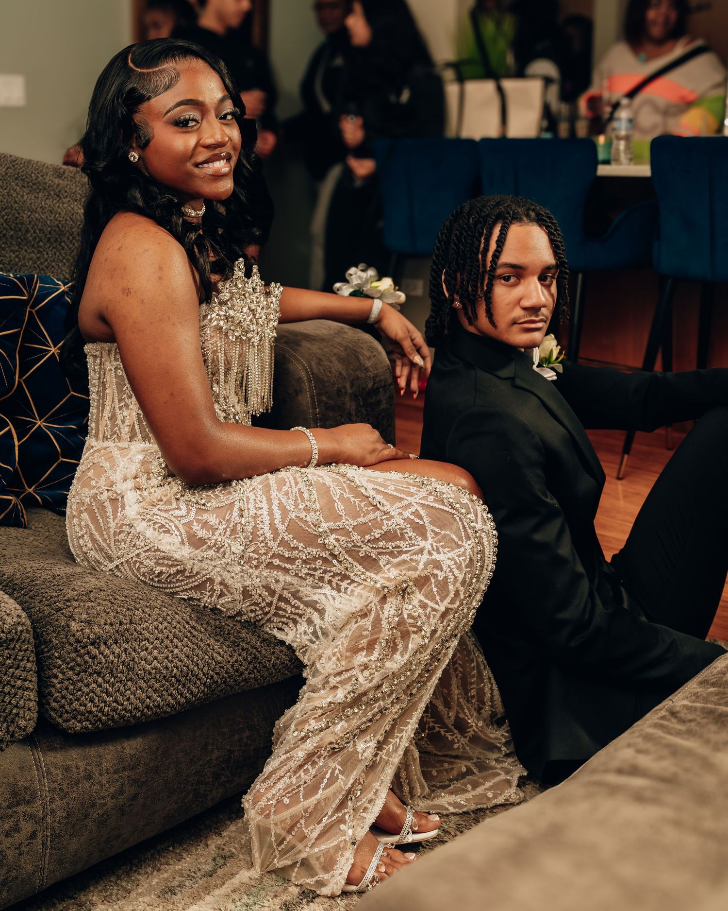 Elegant pair posing on couch in formal attire at special event.