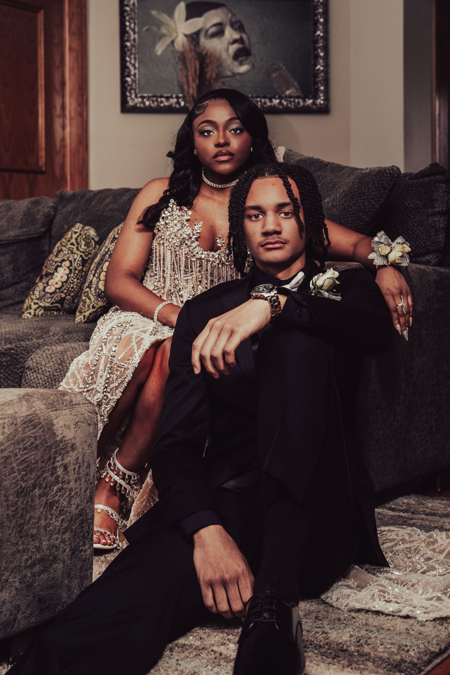 Dramatic portrait on couch featuring sparkly dress and classic black tuxedo.