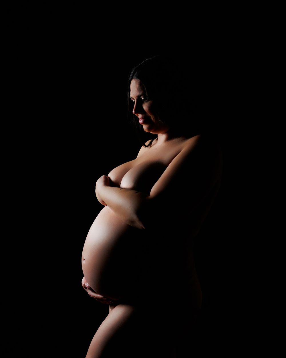Artistic black and white maternity silhouette series showing progression of pregnancy against dark background.