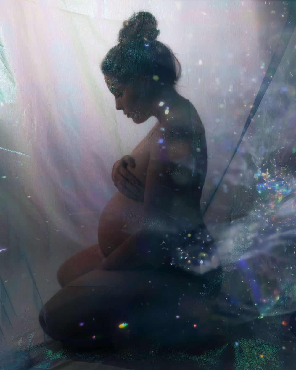 Ethereal maternity portrait with magical sparkles and light beams creating a dreamy atmosphere.