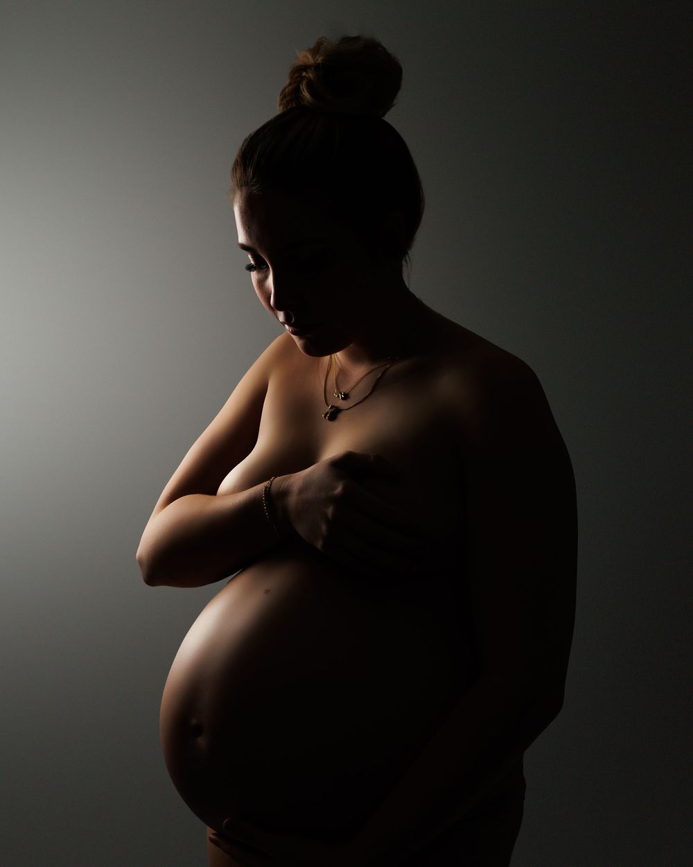 A series of artistic nude silhouettes against a dark background with dramatic side lighting creating shadows and contours.