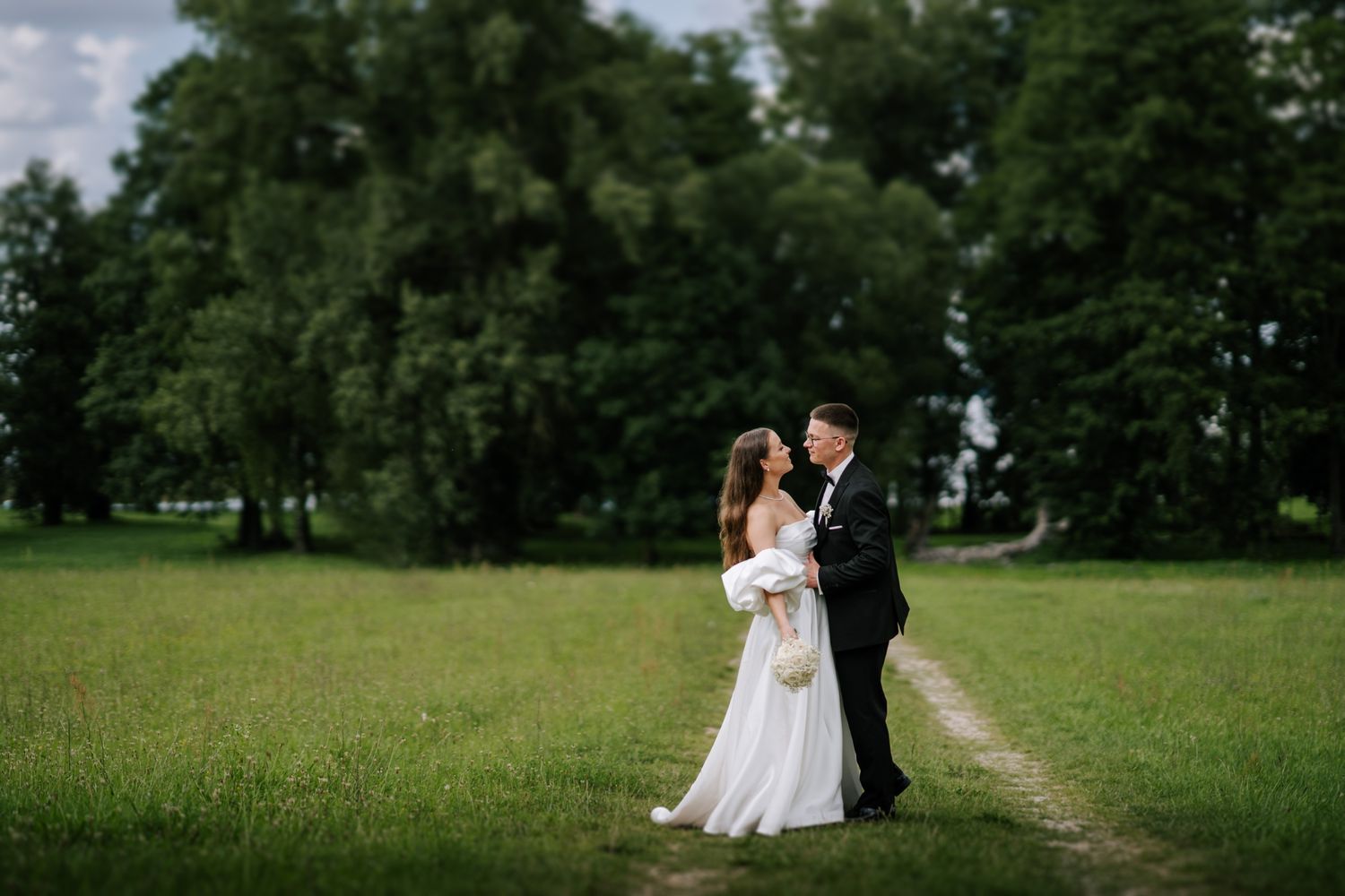 Wedding couple shares intimate moments in a lush green summer garden.