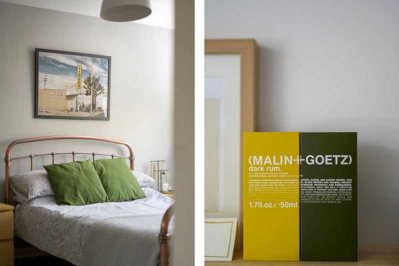 A serene bedroom interior with neutral walls, green accent pillows, and modern minimalist decor.