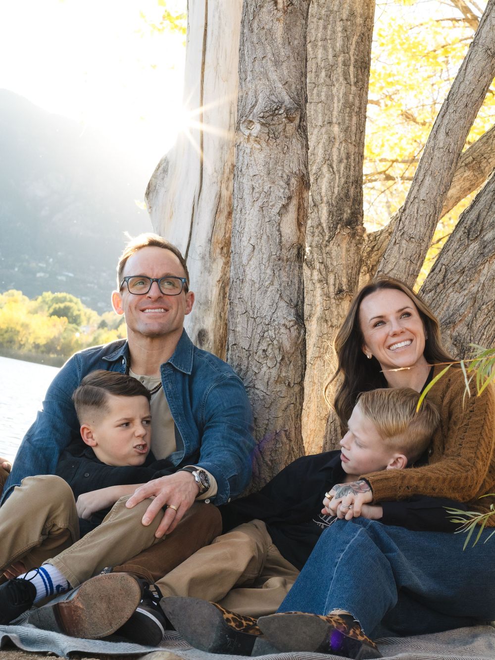 Family members relaxing together on a wooden deck during golden hour, sharing casual moments in casual attire.