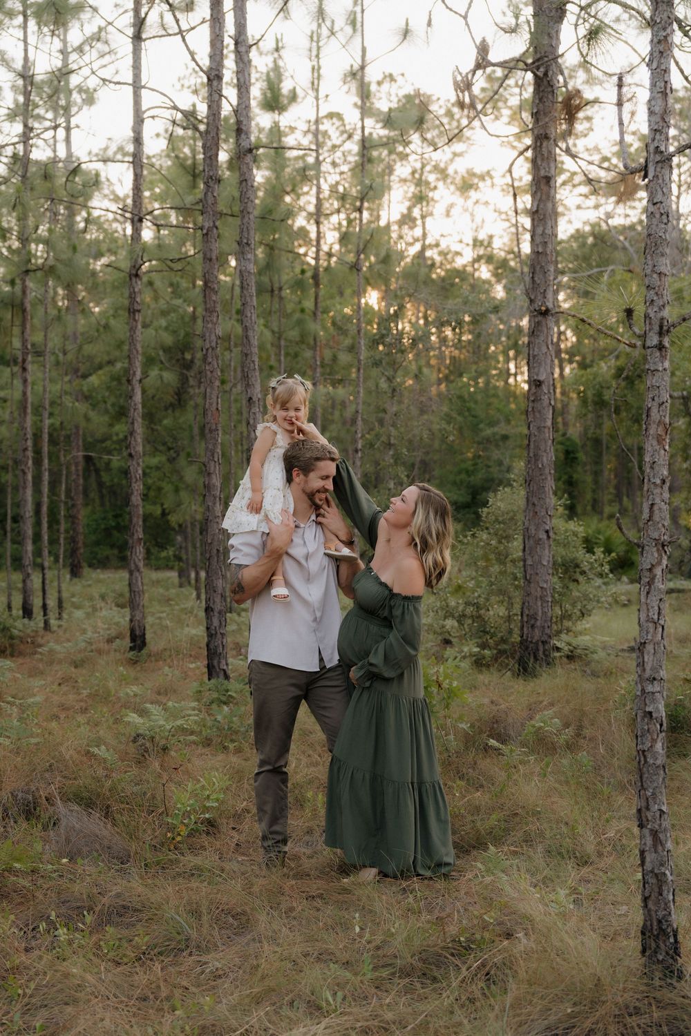 A couple dances and twirls together in a serene pine forest setting during golden hour.