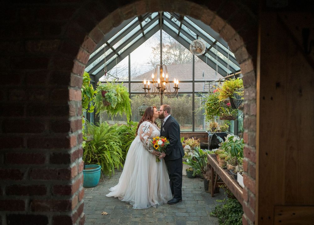 A romantic greenhouse wedding ceremony with lush greenery and natural light streaming through glass panels.