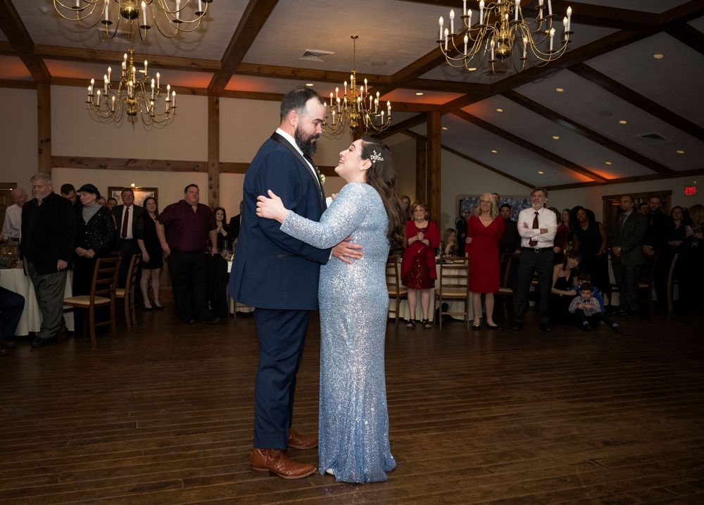 Couple dancing together in an elegant ballroom with crystal chandeliers overhead during a romantic evening celebration.