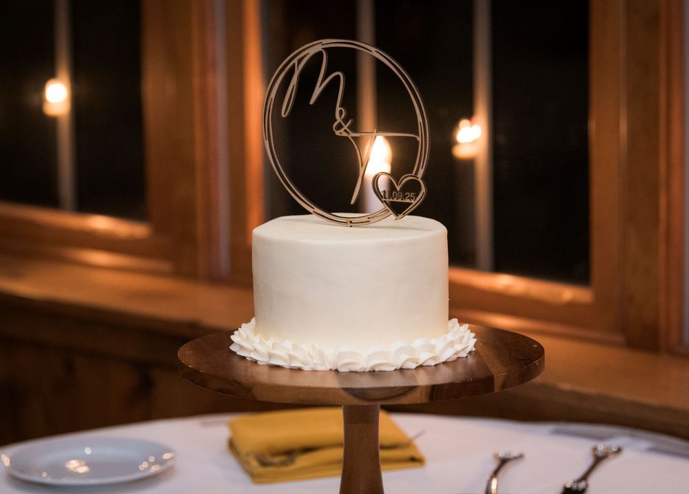 Wedding cake and dessert table display with elegant decorations and soft lighting at an indoor reception.