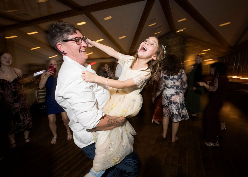 Couples dancing together at a dimly lit reception venue during a celebration.