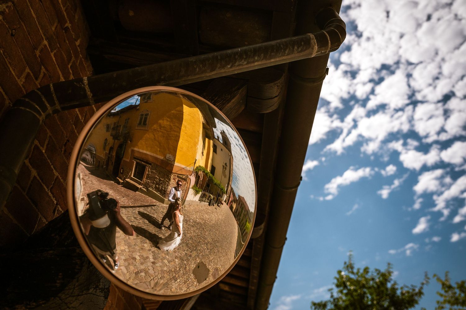 Trouwkoppel weerspiegeld in straatspiegel tijdens destination wedding in Italië, creatief vastgelegd door Bart Boodts.