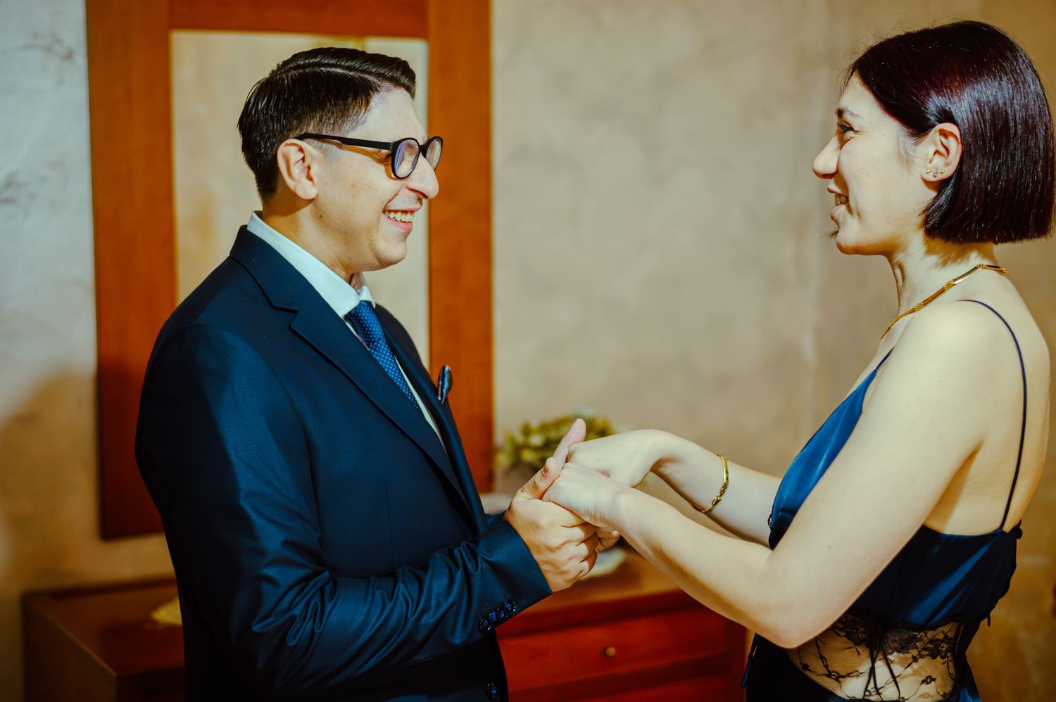 Two people sharing a joyful moment during formal event preparations.