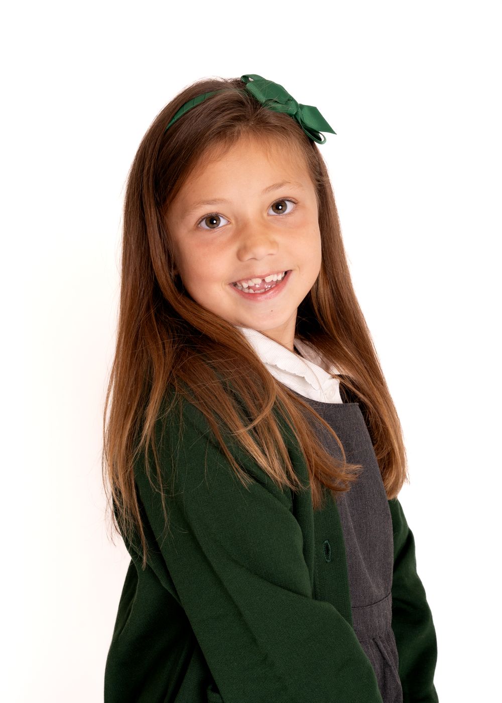 A child in a dark green school uniform jacket poses in four different playful expressions.