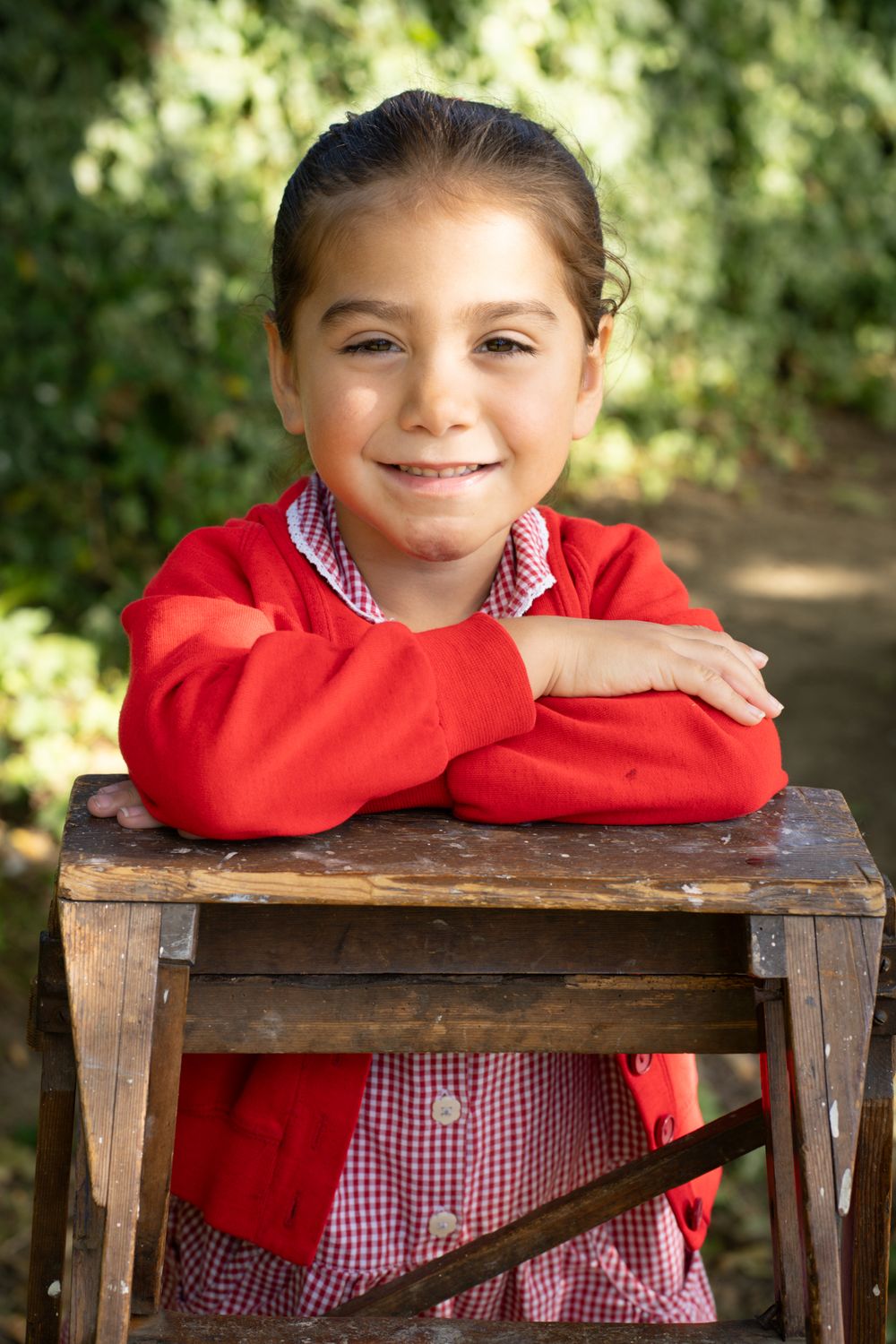 A sequence of casual poses with a red sweater and checkered top while leaning on a rustic wooden surface.