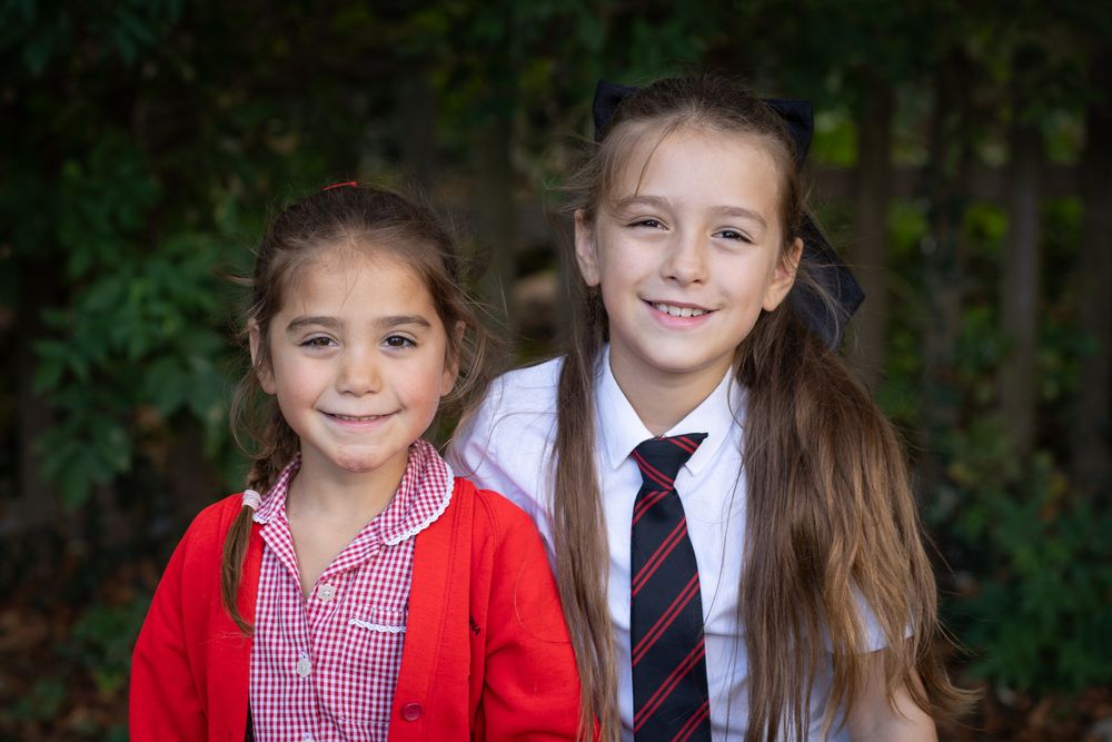 A series of six connected portrait photos showing children in red and white school uniforms against a dark background.