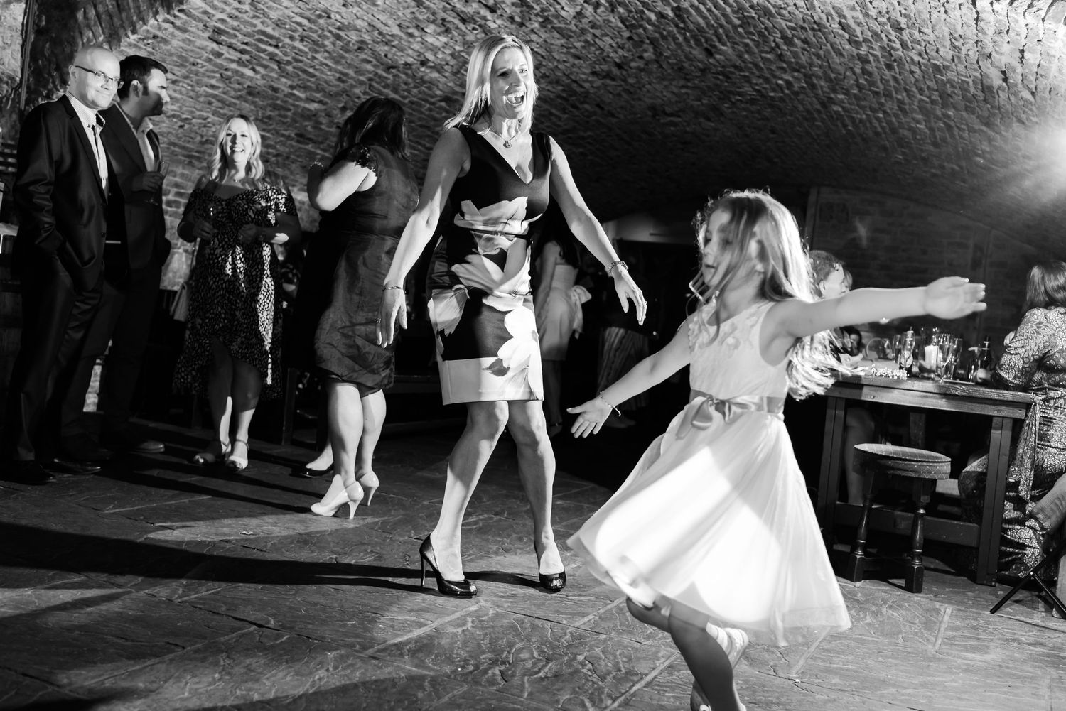 A joyful celebration with wedding guests dancing in a historic underground venue.