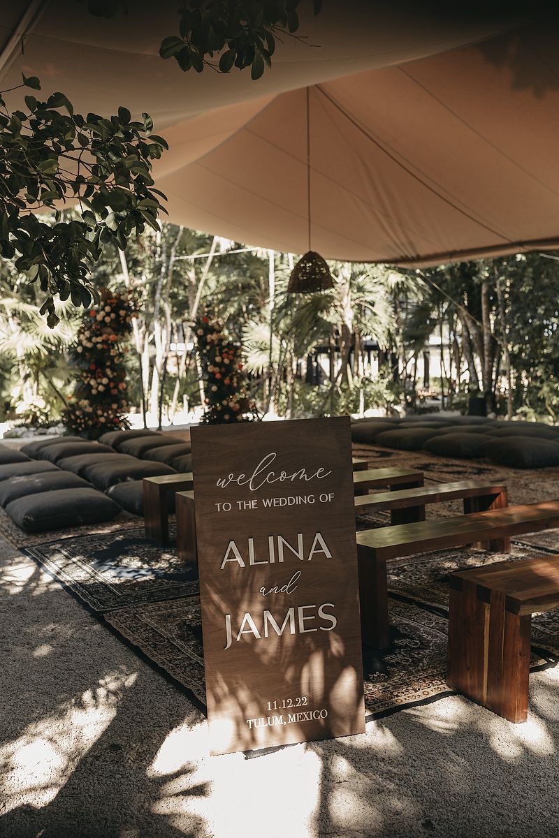 Rustic wedding welcome sign for Alina and James, dated 11.12.22 in Tulum, Mexico, set under an elegant tent.