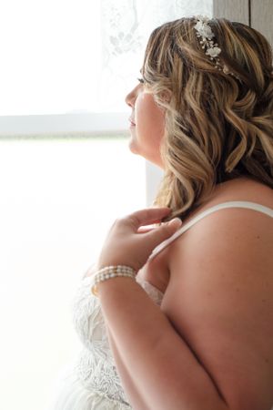 Close-up side view of bridal hairstyle with crystal headpiece and wavy blonde hair.