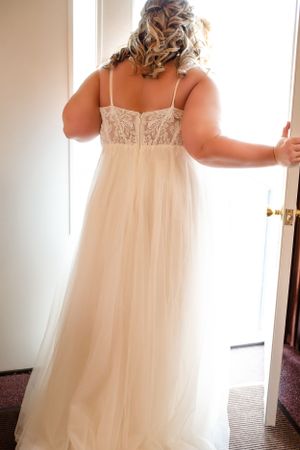 Back view of wedding dress showing detailed lace bodice and flowing tulle skirt.