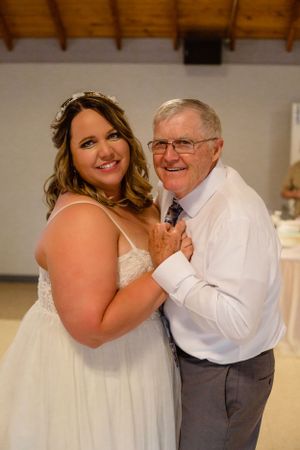 Sweet dance moment captured at wedding reception with wooden ceiling beams.
