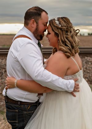 Intimate wedding portrait showing a tender embrace near railroad tracks.