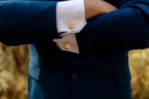 Close-up detail of gold cufflinks on a navy blue suit sleeve.