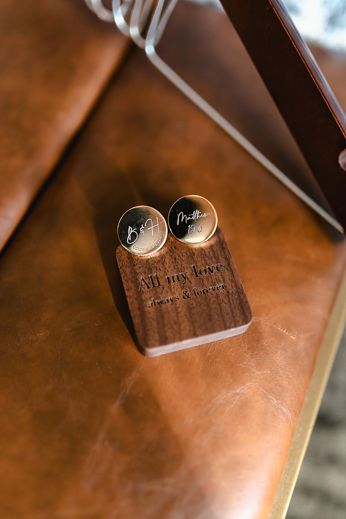 Engraved silver cufflinks displayed on a brown leather surface.