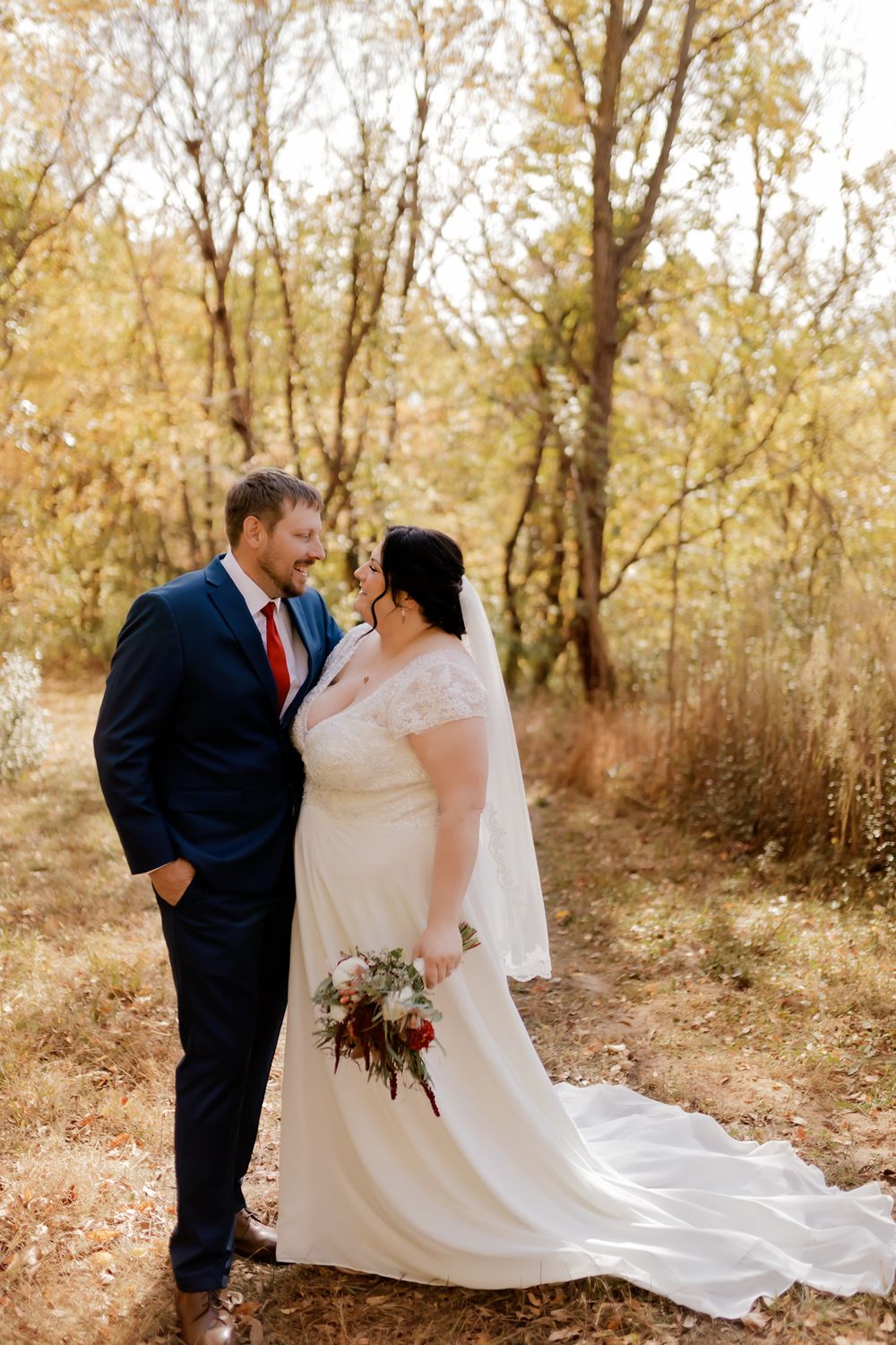 Romantic wedding portrait in a sunlit autumn forest with fall foliage.
