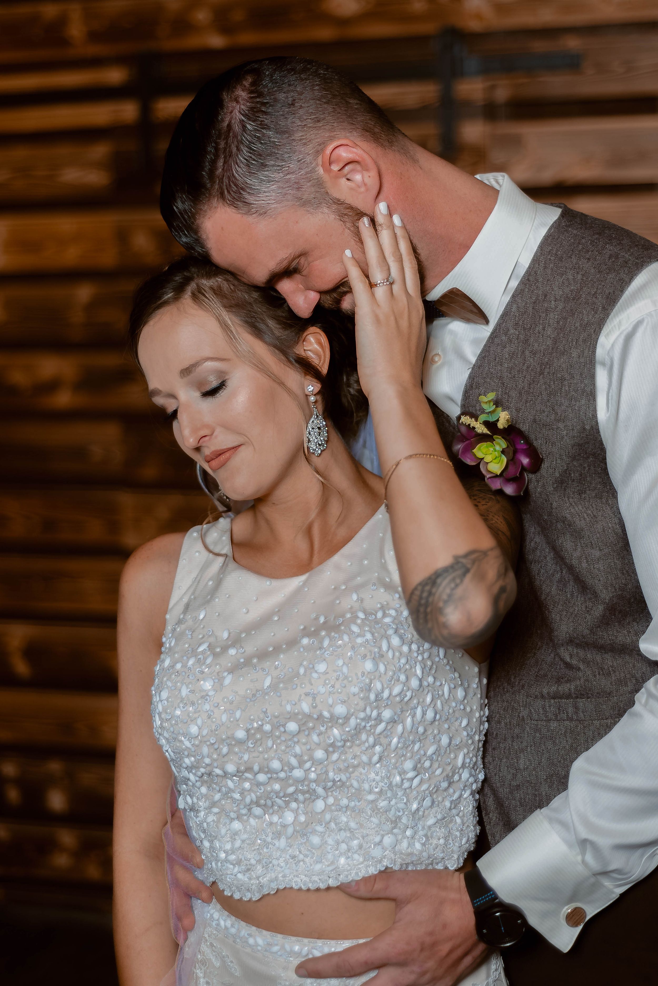 Intimate moment between newlyweds during their first dance in a rustic wooden venue.