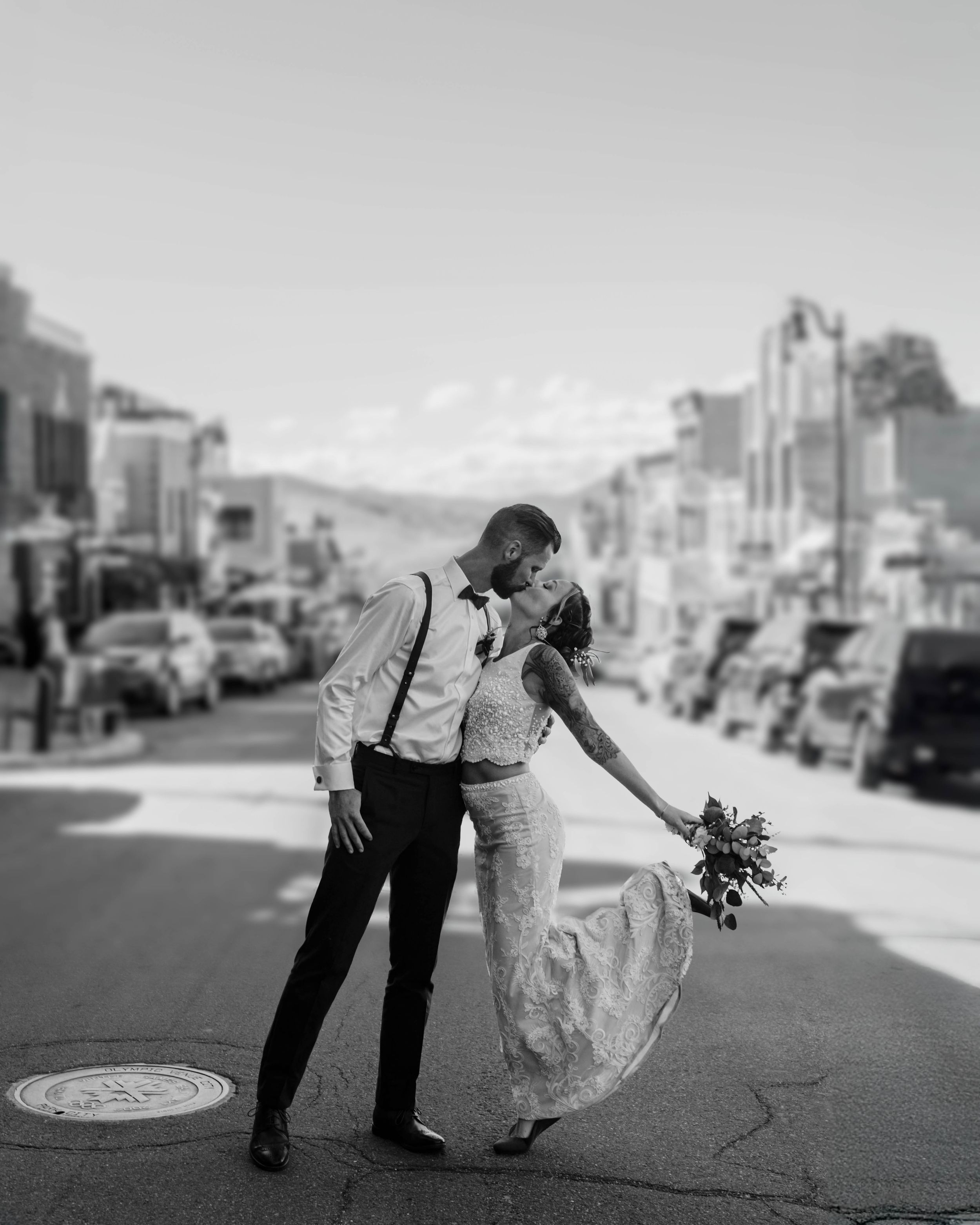 A romantic black and white wedding photo of a couple sharing an intimate moment on a city street.