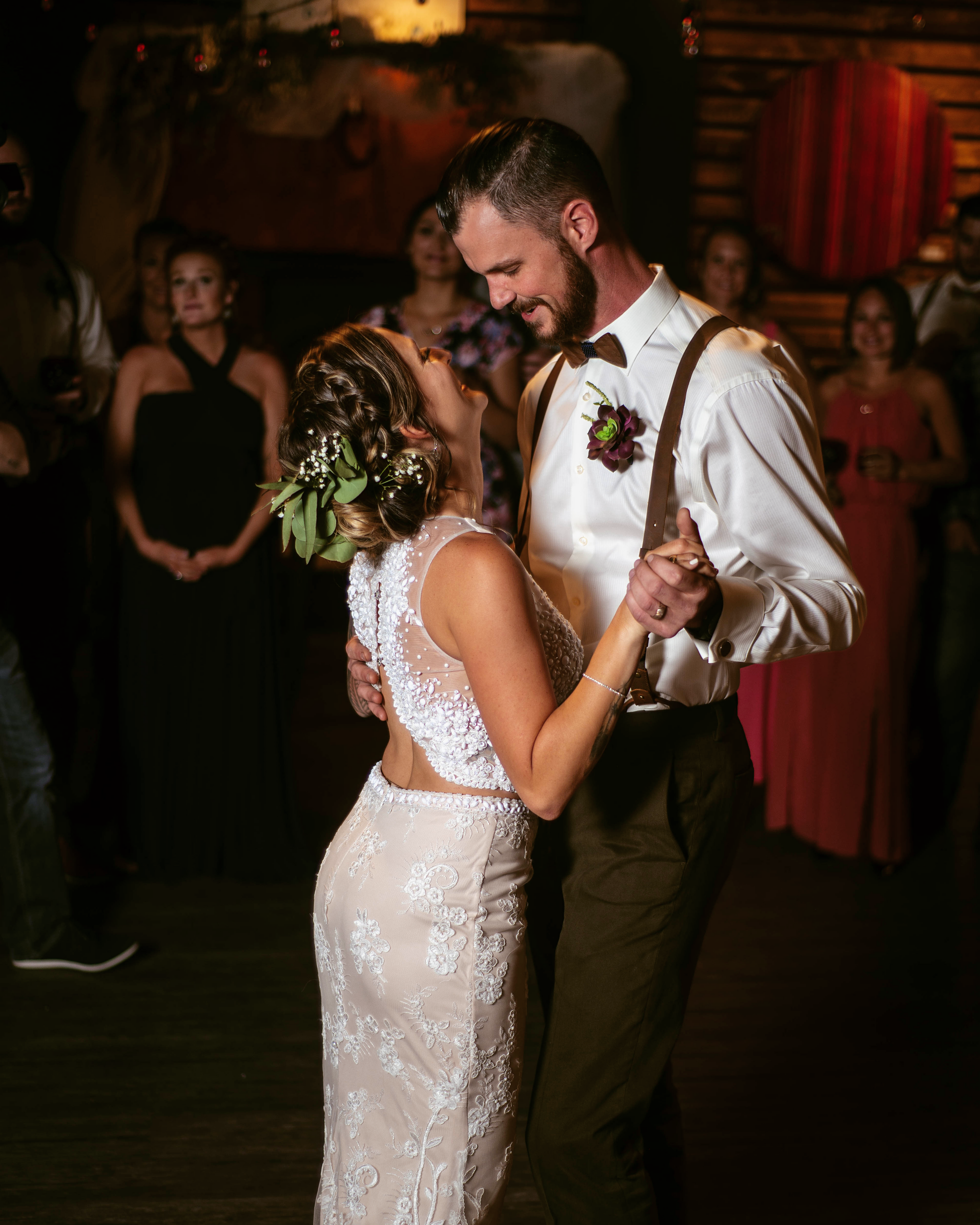 Newlyweds sharing their first dance in a dimly lit rustic venue.