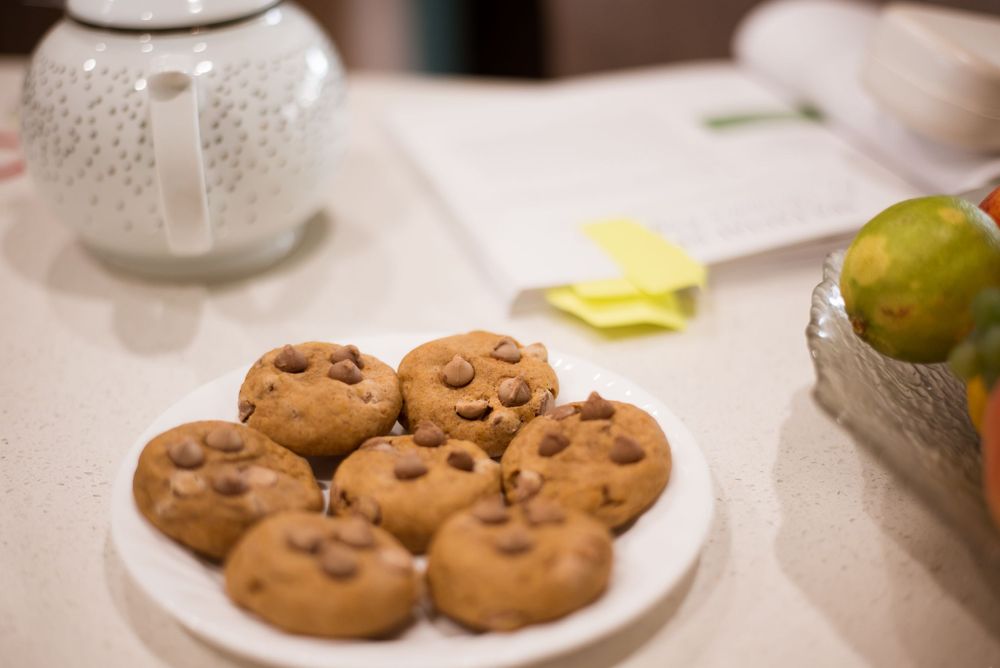A plate of freshly baked chocolate chip cookies on a white tablecloth.