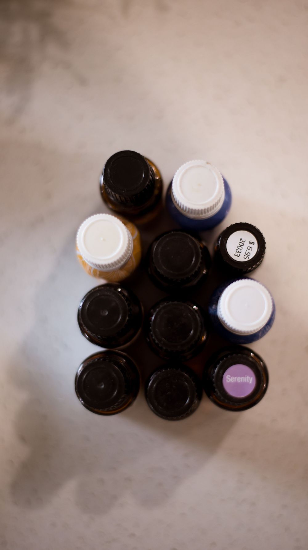 An overhead view of various essential oil bottles with black and white caps arranged in a triangular pattern.