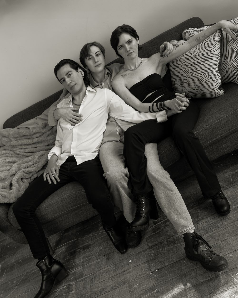 Three people lounging casually together on a couch in black and white photography.