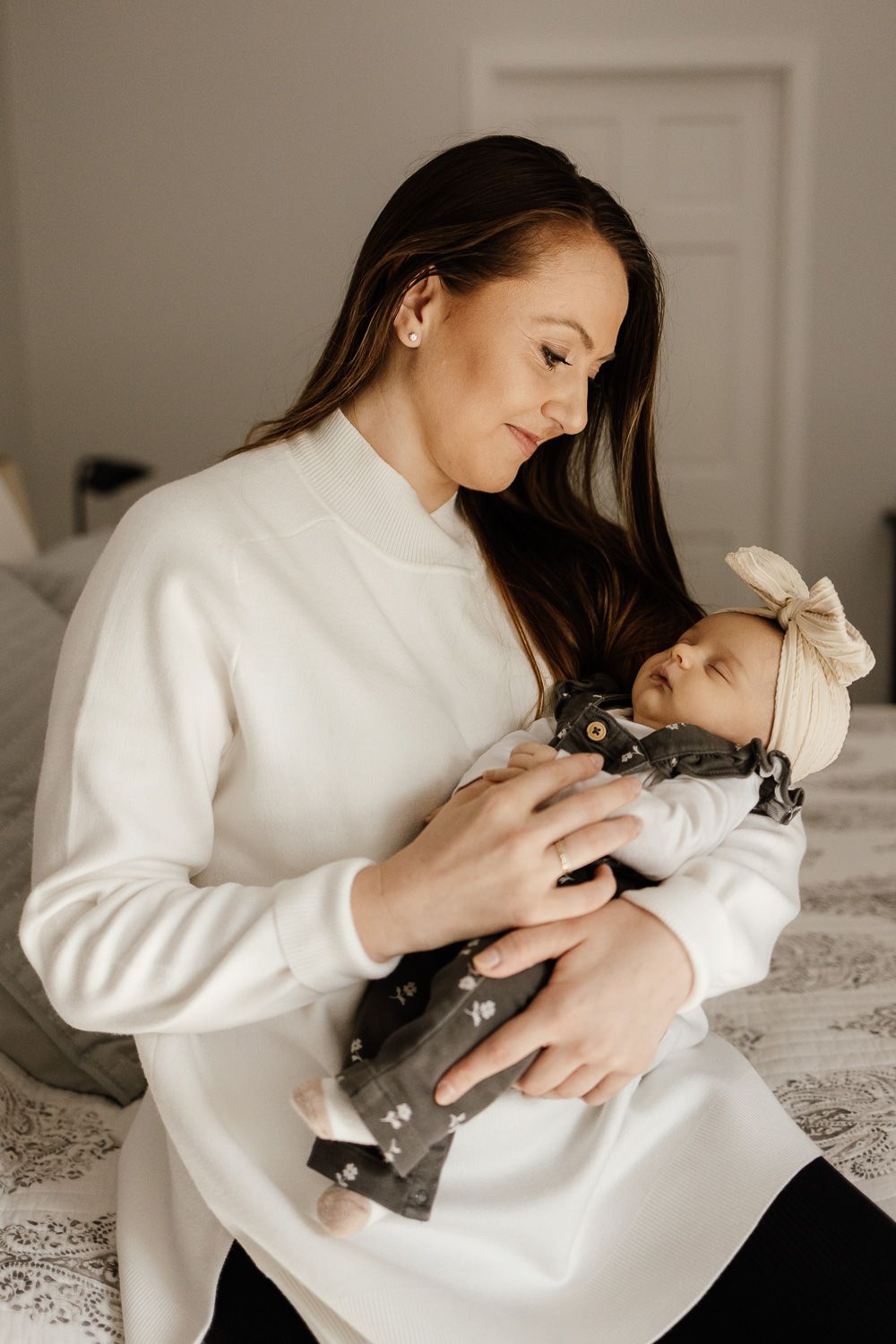 A mom holds her newborn baby during a baby-led in-home lifestyle photo session in San Jose